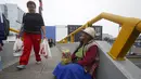 Warga berjalan di dekat Alejandra Baldani, nenek 78 tahun yang berjualan permen di jembatan penyeberangan di distrik San Borja, Lima, 22 Oktober 2015. Nenek Baldani mendapatkan sekitar USD 3 per hari dari hasil berjualan permen. (REUTERS/Mariana Bazo)
