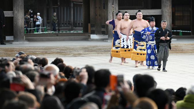 Juara Grand Sumo, Kakuryu (keempat kanan) tiba untuk melakukan upacara mengentakkan kaki menyambut tahun baru di Kuil Meiji, Tokyo, 8 Januari 2019. Ritual penyambutan tahun baru itu melibatkan tiga juara pegulat sumo. (Toshifumi KITAMURA/AFP)