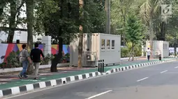 Pejalan kaki melintas di depan kontainer tiket Asian Games 2018 yang berdiri di sepanjang trotoar Jalan Pintu 1 Senayan, Jakarta, Selasa (7/8). Langkah Panitia Penyelenggara Asian Games 2018 (INASGOC) ini menuai kritik. (Merdeka.com/Iqbal Nugroho)