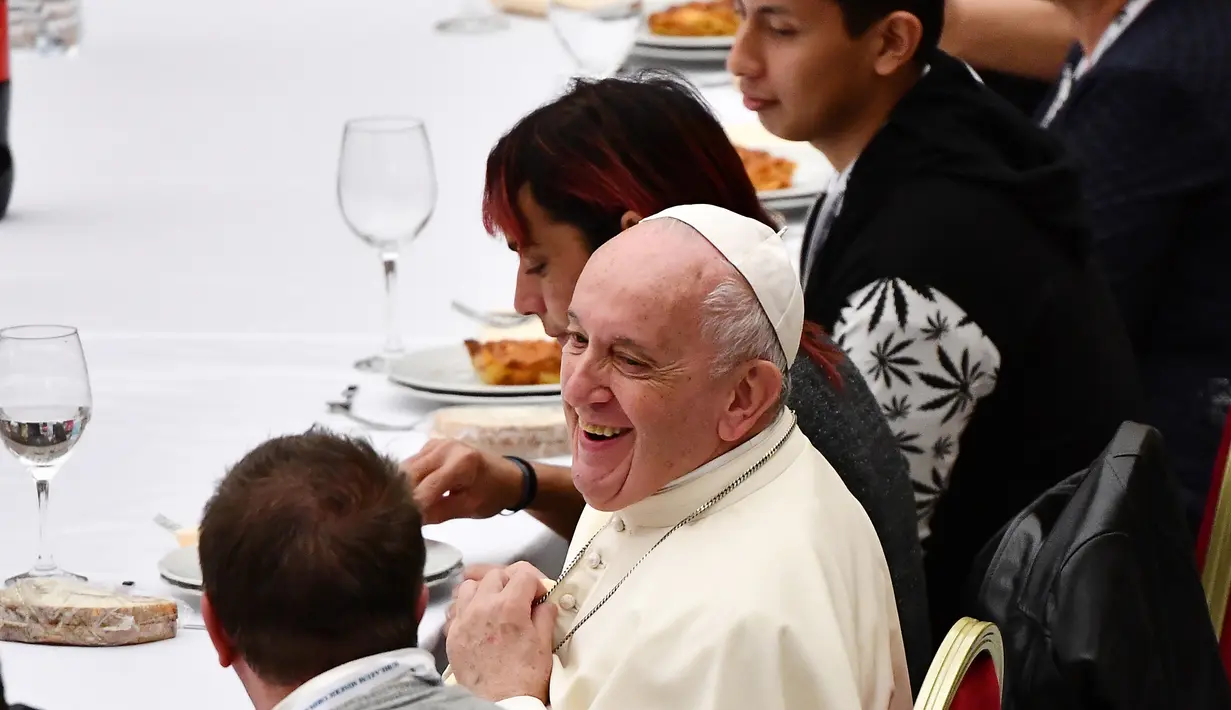 Paus Fransiskus duduk di sebuah meja dalam jamuan makan siang di Aula Paul VI, Vatikan, Minggu (17/11/2019). Paus Fransiskus mengundang sekitar 1.500 orang miskin, tunawisma, imigran dan pengangguran untuk makan siang dalam memperingati Hari Orang Miskin Sedunia. (Vincenzo PINTO / AFP)