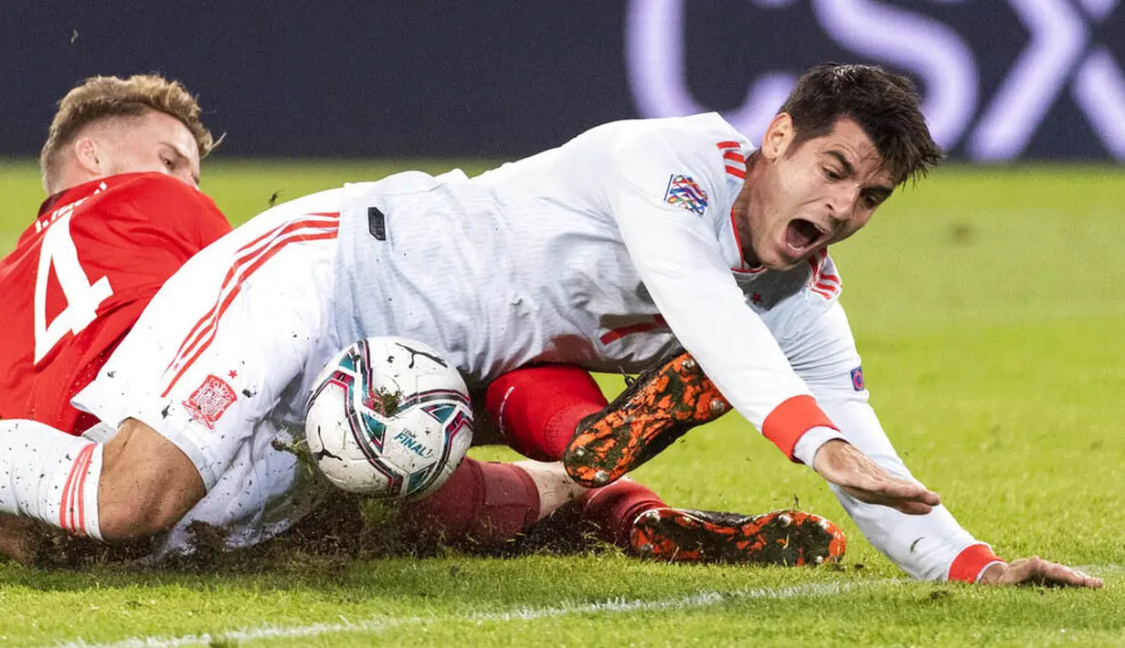 Striker Spanyol, Alvaro Morata, berebut bola dengan pemain Swiss, Nico Elved, pada laga UEFA Nations League di Stadion St. Jakob-Park, Minggu (15/11/2020). Kedua tim bermain imbang 1-1. (Alessandro della Valle/Keystone via AP)