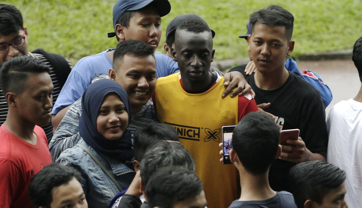 Pemain Arema FC, Makan Konate, foto bersama dengan fans usai sesi latihan di Stadion Gajayana, Malang, Kamis (11/4). Setelah sesi latihan, pemain Arema FC melayani permintaan fans untuk foto bersama. (Bola.com/Yoppy Renato)