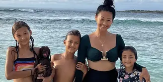 Indah Kalalo bersama tiga anaknya mengenakan bikini two pieces. Dengan atasan bukini long sleeve dan bawahannya serba hitam. (@indahkalalo)
