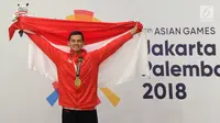 Pesilat Indonesia, Aji Bangkit Pamungkas mengibarkan bendera Merah Putih usai meraih medali emas ke-16 untuk Indonesia dalam babak final Kelas I Putra Asian Games 2018 di TMII, Jakarta, Senin (27/8). (Merdeka.com/Arie Basuki)