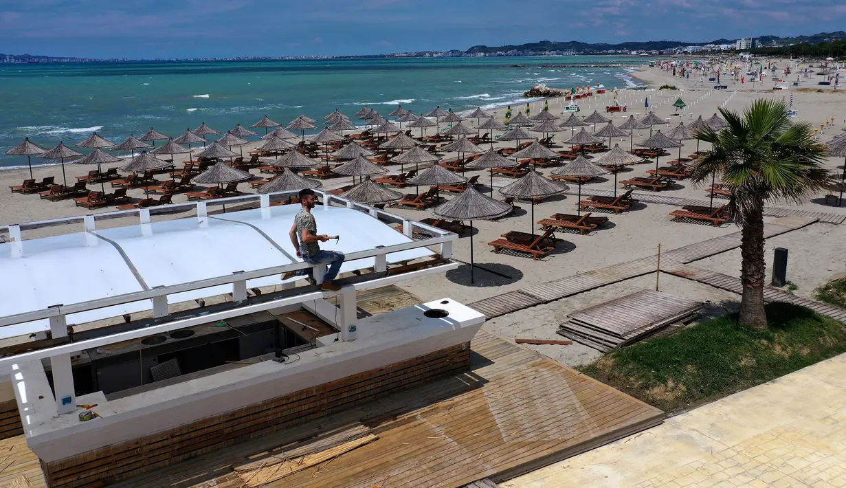 Foto udara pada 1 Juni 2020 menunjukkan payung-payung jerami di sebuah pantai di Qerret, dekat kota Kavaja, Albania. Rencananya pada 6 Juni mendatang, semua pantai umum akan dibuka untuk wisatawan setelah Albania menerapkan langkah-langkah pelonggaran pencegahan virus corona. (SHKULLAKU / AFP)