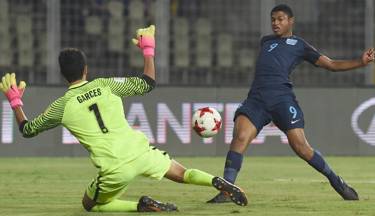 Striker Inggris, Rhian Brewster (kanan) mencetak gol ke gawang Amerika Serikat yang dikawal Justin Garces pada laga perempatfinal Piala Dunia U-17 2017 di Jawaharlal Nehru Stadium, India (21/10/2017). Rhian Brewster dinobatkan sebagai top skor Piala Dunia U-17 2017 di India dengan raihan 8 gol. Ketajaman Rhian Brewster turut membawa Inggris menjadi juara setelah mengalahkan Spanyol 5-2 di laga final, di mana Rhian Brewster ikut menyumbang satu gol. (AFP/Indranil Mukherjee)