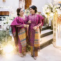 Saat acara martupol atau pertunangan yang dilakukan di gereja, kedua mama tampil stunning dengan kebaya dan songket nuansa warna ungu berry. Lihatlah model kerah kebaya Ibu Yakup yang outstanding. [Foto: Instagram @regisbridalshoes]