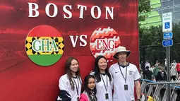 Satu keluarga suporter Inggris berfoto di depan instalasi pertandingan Inggris melawan Ghana di area Gillette Stadium, Foxborough, Boston, AS, Senin (23/6/2026). Ribuan pendukung kedua tim memadati stadion untuk menyaksikan laga fase grup Piala Dunia 2026. (KLY Sports/Hery Kurniawan)