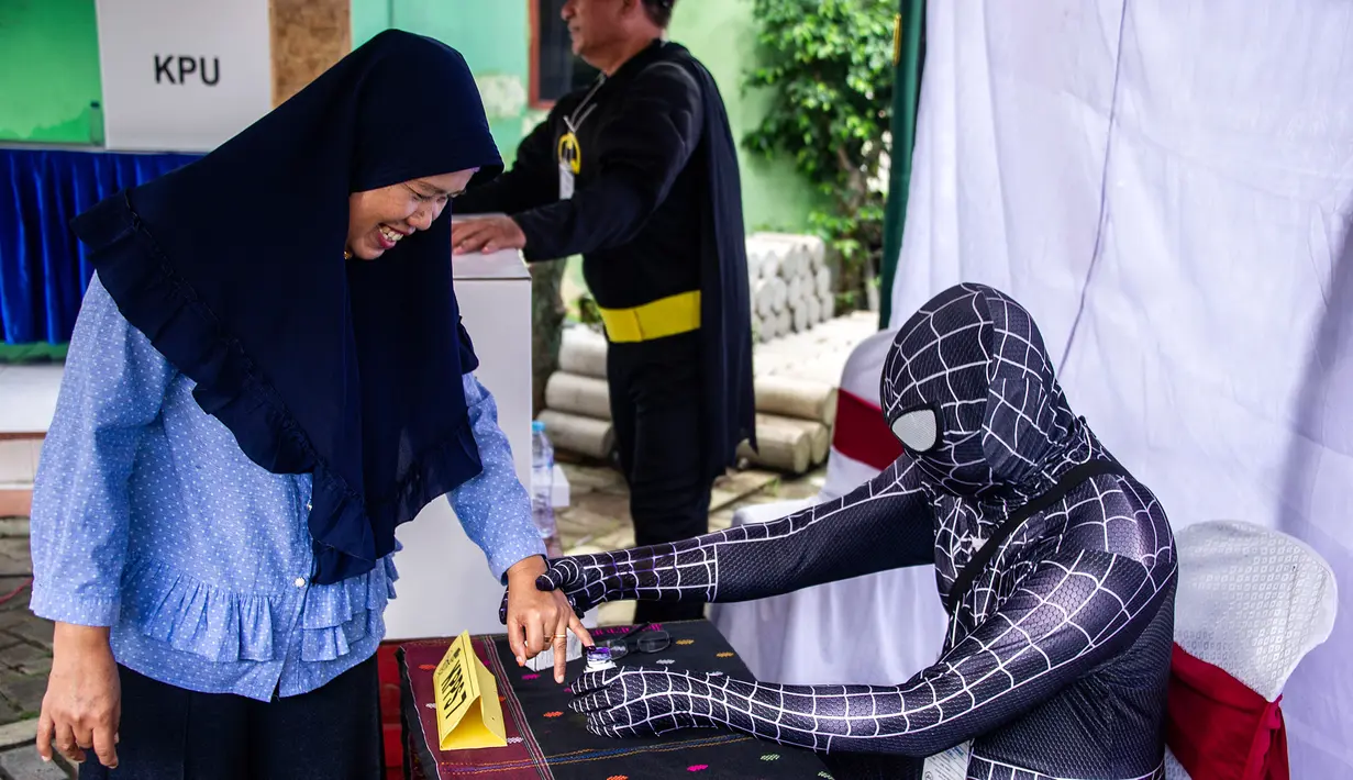 Petugas Kelompok Penyelenggara Pemungutan Suara (KPPS) berkostum superhero Venom membantu warga mencelupkan jari ke tinta dalam Pemilu 2019 di sebuah TPS di Surabaya, Jawa Timur, Rabu (17/4). Petugas KPPS berharap menarik pemilih, khususnya milenial. (Juni Kriswanto/AFP)