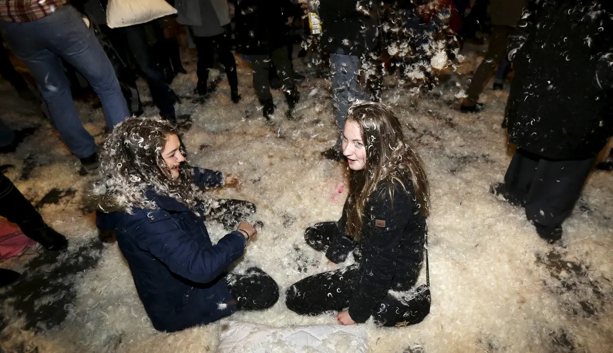 Dua orang wanita tertimbun kapas saat mengikuti flash mob perang bantal selama empat menit di Old Town Square di Praha,Ceko (22/12). flash mob perang bantal ini dilakukan jelang pergantian akhir tahun. (REUTERS/ David W Cerny)