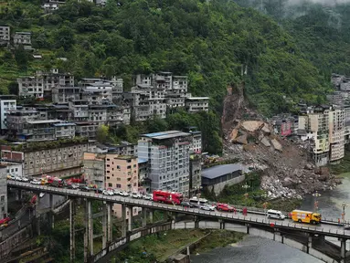 Kendaraan penyelamat bersiaga di jembatan saat tim penyelamat melakukan operasi pencarian dan penyelamatan di lokasi tanah longsor di Kabupaten Pengshui, Chongqing, Tiongkok barat daya, Sabtu, 18 Juli 2026. (AP Photo/Andy Wong)