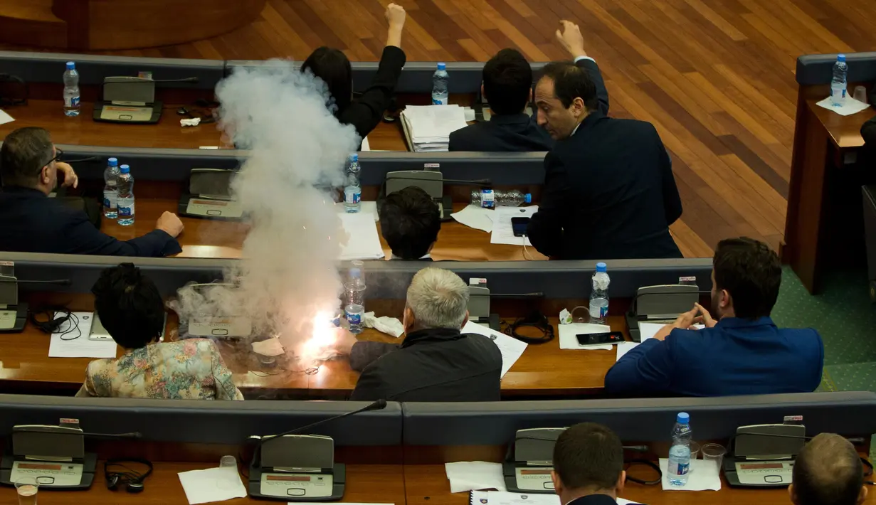 Seorang anggota parlemen Partai Vatevendosje menyalakan tabung gas air mata dalam sesi sidang di Pristina, Kosovo, Rabu (21/3). Aksi dilakukan demi mencegah pemungutan suara terkait masalah kesepatakan perbatasan dengan Montenegro (AP Photo/Visar Kryeziu)
