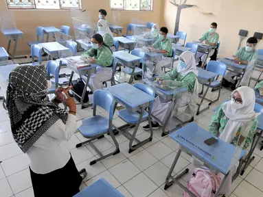 Guru melakukan kegiatan belajar tatap muka dengan penerapan protokol kesehatan COVID-19 di SMAN 2 Cibinong, Kabupaten Bogor, Jawa Barat, Rabu (17/3/2021). Sebanyak 170 sekolah di Kabupaten Bogor mulai menggelar uji coba pembelajaran secara tatap muka hingga 10 April 2021. (merdeka.com/Arie Basuki)