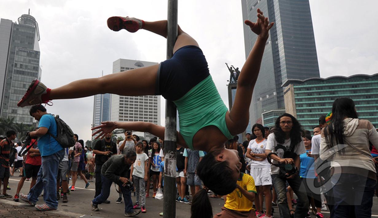 Pegiat 'Pole Dance' beraksi di tiang rambu lalu lintas saat Car Free Day di Bundaran HI, Jakarta, Minggu (18/1/2015). (Liputan6.com/Miftahul Hayat)