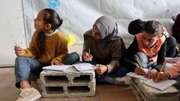 Sekolah Mada menjadi ruang untuk melanjutkan proses belajar bagi anak-anak pengungsi Palestina yang terpaksa meninggalkan rumah mereka. Tampak dalam foto, anak-anak pengungsi Palestina mengikuti belajar mengajar di dalam tenda di Sekolah Mada, kamp pengungsi Jabalia, Jalur Gaza Utara pada 13 April 2026. (Omar AL-QATTAA/AFP)