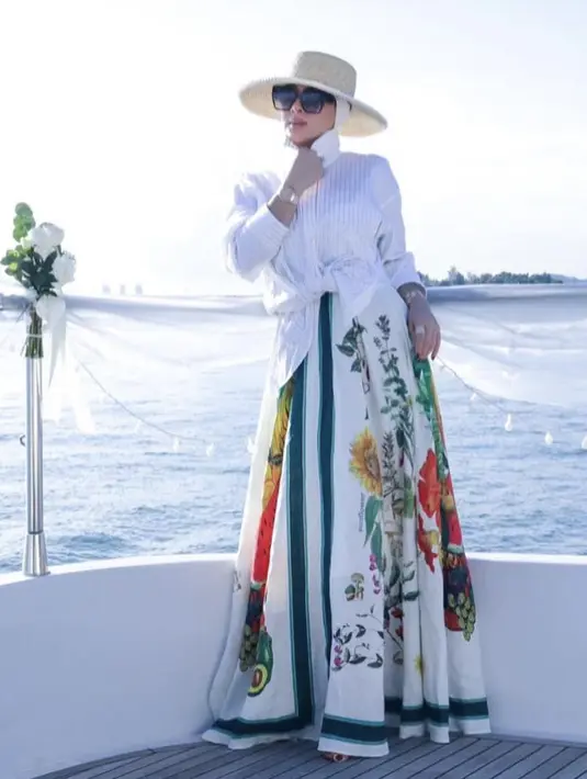 <p>Untuk tampilan ke-dua, Syahrini berpose mengenakan kemeja putih diatas dress bermotif bunga dan buah dari brand Alemais. Dress linen tersebut diketahui seharga Rp6,9 jutaan.&nbsp;@princessyahrini</p>
