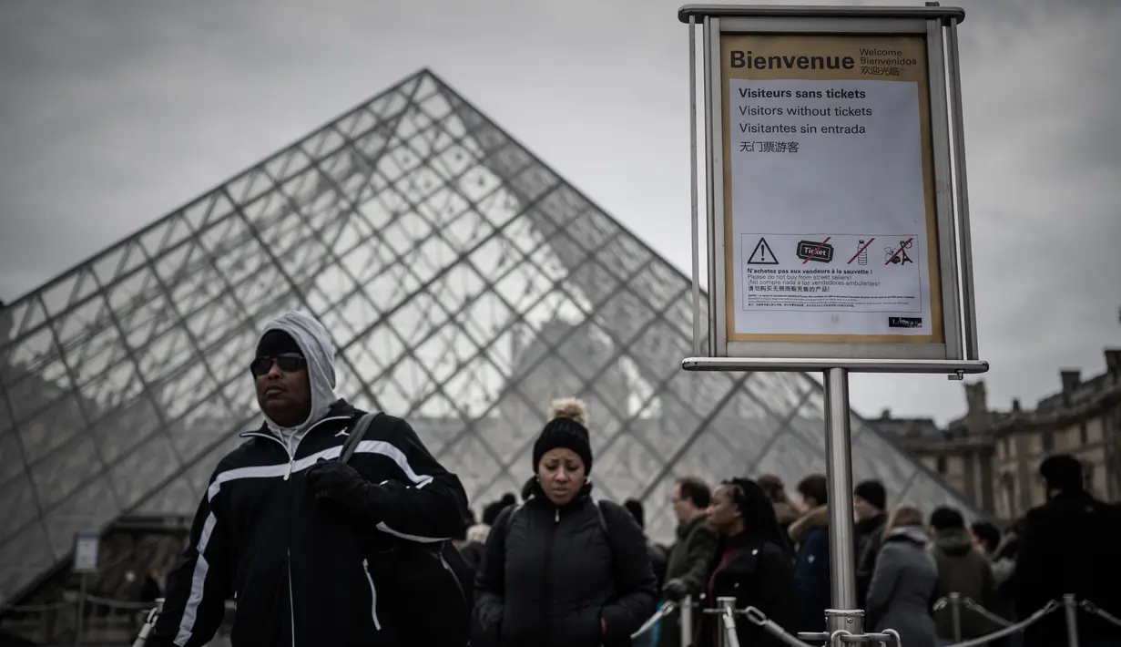 Pengunjung mengantre di luar Pyramid, pintu masuk utama menuju museum Louvre, di Paris, Rabu (4/3/2020). Louvre di Paris, museum yang paling banyak dikunjungi di dunia, kembali dibuka setelah pegawai yang khawatir dengan penularan virus corona setuju kembali masuk kerja. (Philippe LOPEZ/AFP)