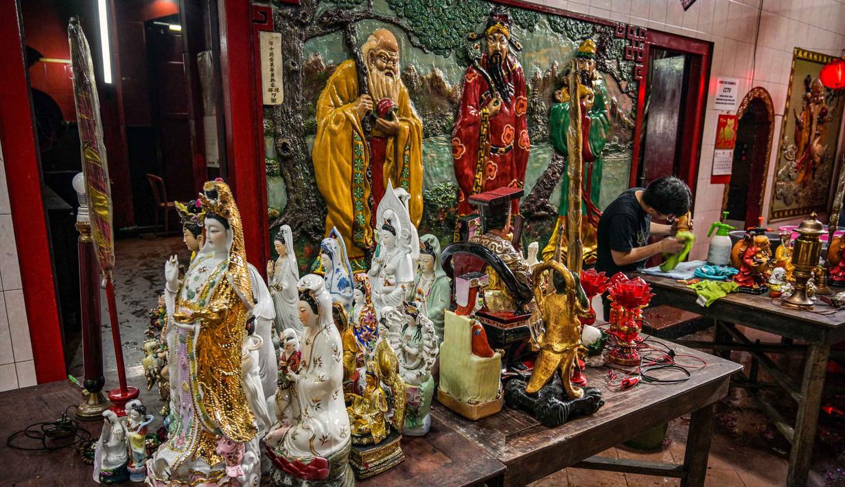 Untuk diketahui, tradisi bersih-bersih rupang merupakan ritual membersihkan patung dewa-dewi dengan air hangat yang ditaburi bunga dan minyak khusus, diikuti dengan mengganti kain patung dan mempersembahkan doa. Tampak dalam foto, para sukarelawan membersihkan patung-patung dewa di Kuil Hong San Ko Tee, Surabaya, Jawa Timur, pada Rabu 11 Februari 2026. (JUNI KRISWANTO/AFP)