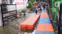 Petugas membuat jembatan apung saat banjir melanda Perumahan Periuk Damai, Tangerang, Banten, Selasa (23/2/2021). Adanya jembatan apung mempermudah warga saat melintasi banjir setinggi 2,5 meter di tempat tersebut. (Liputan6.com/Angga Yuniar)