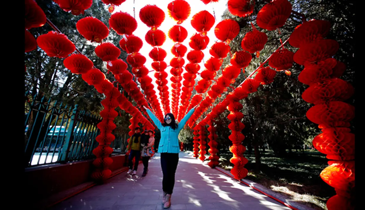 Seorang wanita berpose di bawah lentera kertas, merayakan Tahun Baru Cina, di Ditan Park, Beijing (18/2/2015). Tahun Baru Imlek pada 19 Februari akan menyambut Tahun Domba. (Reuters /Kim Kyung-Hoon)