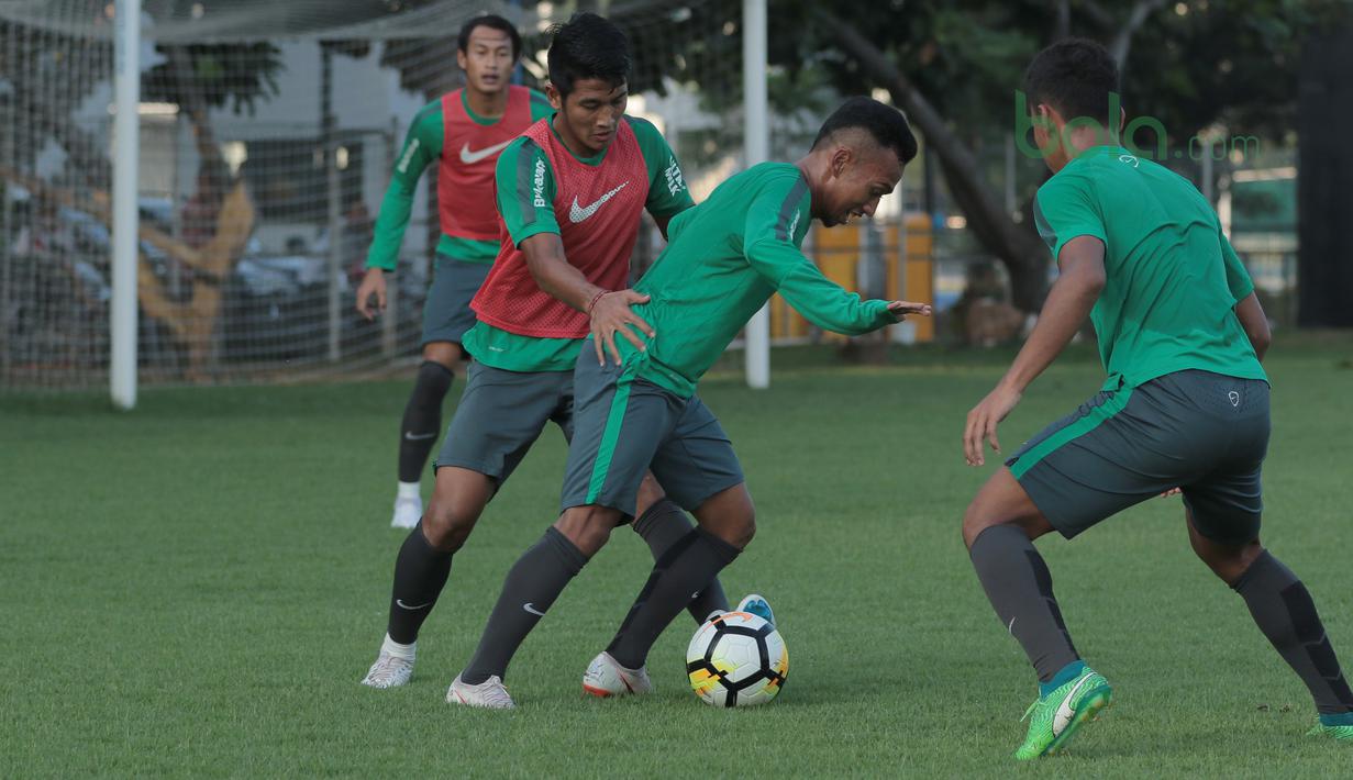 Aksi Irfan Jaya (tengah) melewati rekannya pada sesi latihan di Lapangan ABC Senayan, Jakarta (22/6/2018). Timnas melakukan persiapan untuk melawan Korea pada laga uji coba 23 Juni 2018. (Bola.com/Nick Hanoatubun)