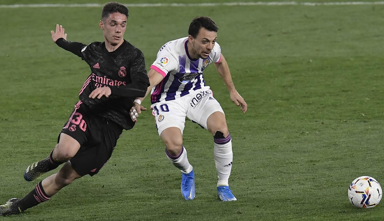 Pemain Real Valladolid, Oscar Plano, berebut bola dengan pemain Real Madrid, Sergio Arribas, pada laga Liga Spanyol di Stadion Jose Zorrila, Minggu (21/2/2021). Real Madrid menang dengan skor 1-0. (AP/Alvaro Barrientos)