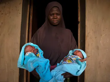Seorang wanita muslim menggendong saudara laki-laki kembarnya yang berumur 4 hari di depan pintu rumahnya di Igbo Ora, Negara Bagian Oyo, Nigeria pada 3 April 2019.  Igbo Ora, sebuah wilayah di bagian barat daya Nigeria ini terkenal dengan anak-anaknya yang terlahir kembar. (REUTERS/Afolabi Sotunde)