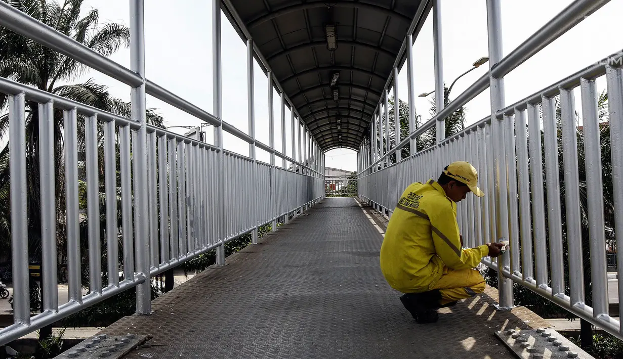 Petugas Dinas Bina Marga DKI Jakarta mengecat jembatan penyeberangan orang (JPO) di Jalan Daan Mogot, Jakarta Barat, Rabu (7/8/2019). Pengecatan ini bagian dari perawatan fasilitas umum agar masyarakat bisa menggunakan JPO dengan baik. (Liputan6.com/JohanTallo)