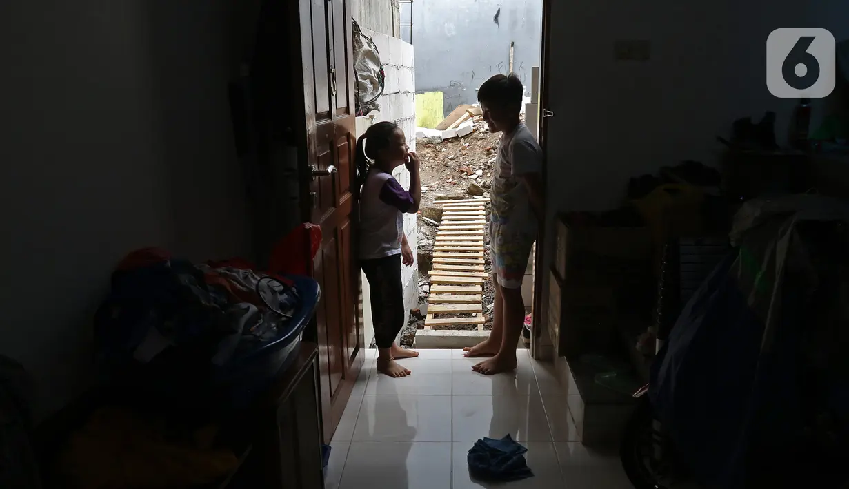 Dua orang anak bermain di depan pintu rumahnya yang terhimpit bangunan gudang di kawasan Mangga Dua Dalam, Jakarta, Kamis (12/12/2019). (Liputan6.com/Herman Zakharia)