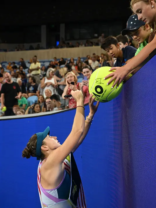 Petenis asal Swiss Belinda Bencic memberikan tanda tangan setelah kemenangannya melawan Viktoriya Tomova dari Bulgaria selama pertandingan tunggal putri mereka pada hari kedua Australia Terbuka di Melbourne, Selasa (17/1/2023). Selain bola-bola, foto dan halaman tertentu majalah tenis menjadi barang favorit yang disodorkan fans ke petenis favoritnya. (WILLIAM WEST / AFP)