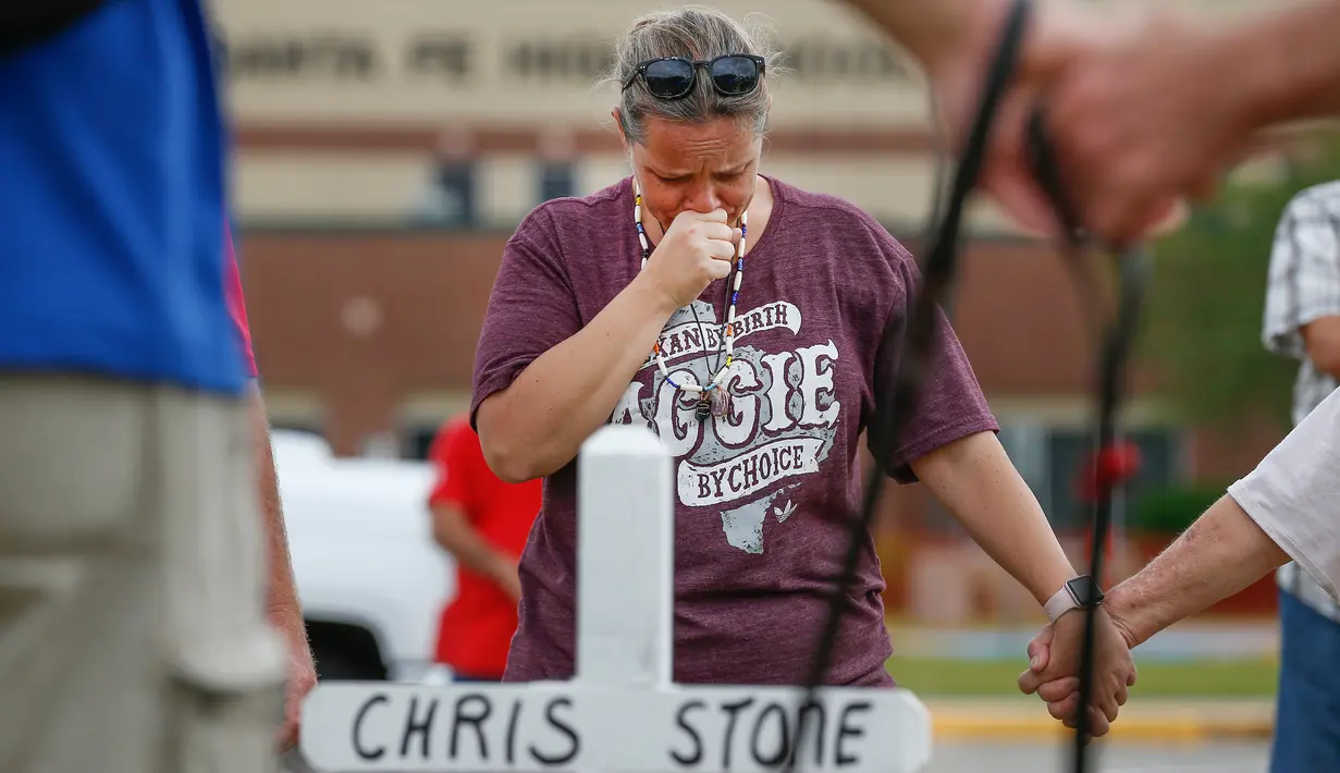 Penduduk Santa Fe, Lori Simmons menangis saat mengheningkan cipta di depan SMA Santa Fe di Texas, AS, Senin (21/5). Korban tewas penembakan Texas terdiri dari delapan siswa dan dua guru. (Steve Gonzales/Houston Chronicle via AP)