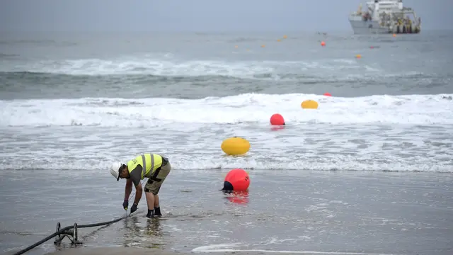 Seorang operator bekerja selama tambatan kabel serat optik bawah laut di pantai Arrietara dekat desa Basque Spanyol Sopelana. ANDER GILLENEA / AFP