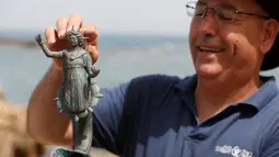 Pekerja Israel Antiquities Authority ( IAA) memegang sebuah temuan berupa patung di pelabuhan kuno dari Taman Nasional Caesarea, Israel, 16 Mei 2016. Peninggalan ini diduga berasal dari jaman Kekaisaran Romawi. (REUTERS / Baz Ratner)