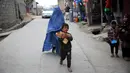 Seorang anak membawa roti gratis dari kota selama lockdown untuk mencegah penyebaran virus corona, pada bulan suci Ramadan di Kabul, Afghanistan (4/5/2020). Muslim di seluruh dunia sedang menjalankan Ramadan, ketika mereka menahan diri dari makan, minum dari subuh hingga senja. (AP/Rahmat Gul)