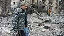Seorang warga lokal berjalan melintasi puing-puing di depan bangunan tempat tinggal yang rusak akibat serangan rudal di Kharkiv pada 23 Januari 2024. (SERGEY BOBOK/AFP)