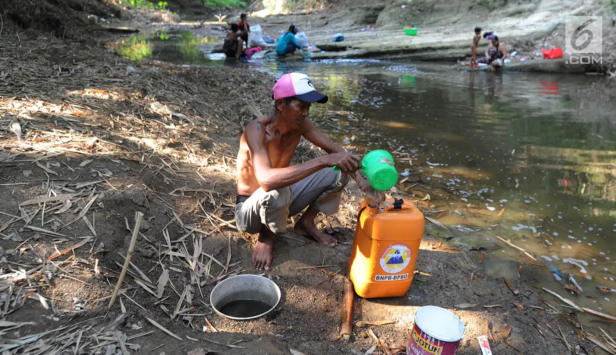 Warga mengambil air dari lubang pada aliran Sungai Cihoe untuk memenuhi kebutuhan sehari-hari termasuk air minum di kawasan Ridogalih, Cibarusah, Bekasi, Minggu (7/7/2019). Sudah lebih dari dua bulan, warga memanfaatkan sisa aliran sungai yang kotor akibat musim kemarau. (merdeka.com/Arie Basuki)