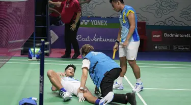 Dokter memeriksa ganda putra Indonesia Yeremia Rambitan yang cedera di dekat rekannya, Pramudya Kusumawardana saat melawan pasangan Malaysia Aaron Chia/Soh Wooi Yik pada perempat final Indonesia Open 2022 di Istora Senayan, Jakarta, Jumat (17/6/2022). Pram/Yere secara dramatis dikalahkan pasangan Malaysia Aaron Chia/Soh Wooi Yik 21-14, 12-21, 20-22. (AP Photo/Dita Alangkara)