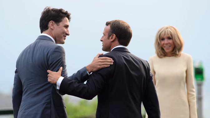 Presiden Prancis Emmanuel Macron (tengah) disaksikan istrinya Brigitte Macron (kanan) menyambut kedatangan Perdana Menteri Kanada Justin Trudeau (kiri) di KTT G7, Biarritz, Prancis, Sabtu (24/8/2019). (Sean Kilpatrick/The Canadian Press via AP)