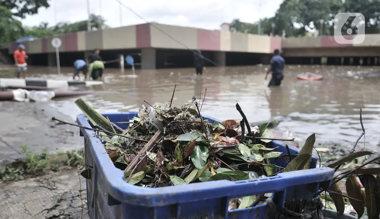 Petugas Pusat Pengelolaan Kompleks (PPK) Kemayoran membersihkan sampah yang muncul akibat banjir di Underpass Kemayoran, Jakarta, Minggu (2/2/2020). Selain melumpuhkan akses, banjir setinggi hingga 5 meter tersebut menyebabkan sampah memenuhi Underpass Kemayoran. (merdeka.com/Iqbal S. Nugroho)