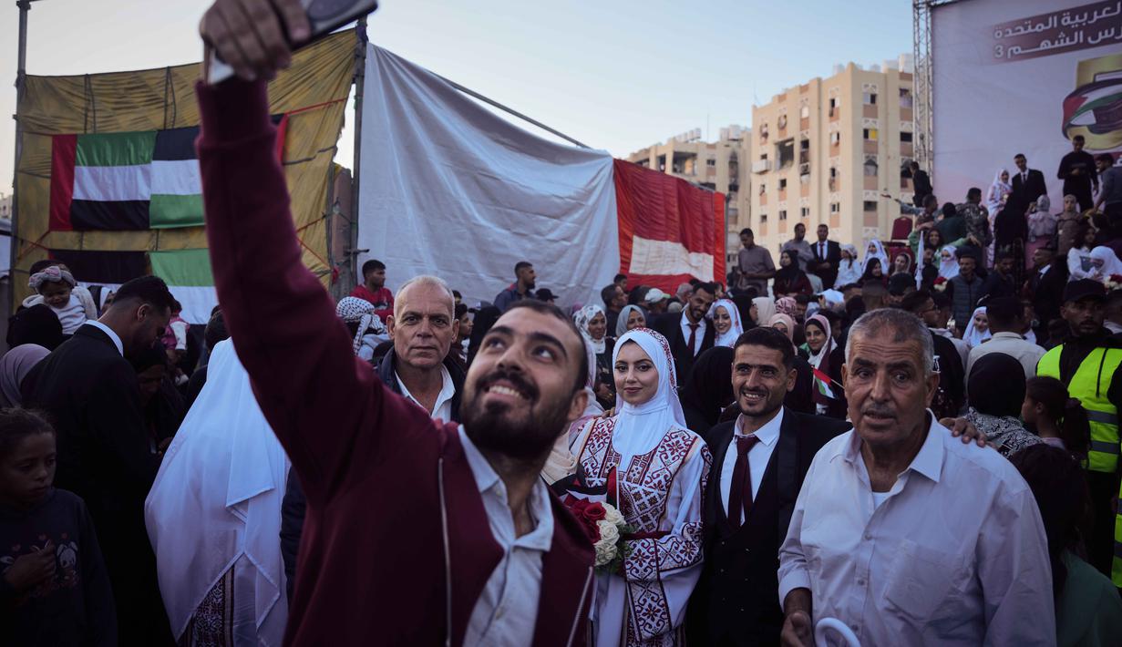 Acara tersebut menjadi ruang bagi masyarakat Gaza untuk merasakan kembali kebahagiaan yang telah lama direnggut oleh agresi dan blokade militer Israel. Tampak dalam foto, pasangan Palestina berpartisipasi dalam upacara pernikahan massal di Kota Hamad, Khan Younis, Jalur Gaza, Selasa 2 Desember 2025. (AP Photo/Abdel Kareem Hana)