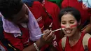 Seorang suporter wanita melukis pipinya dengan gambar bendera Merah Putih jelang semifinal SEA Games 2017 di Stadion Sham Alam Selangor, Malaysia, Sabtu (26/8). Timnas Indonesia U-22 bakal berlaga melawan Malaysia. (Liputan6.com/Faizal Fanani)