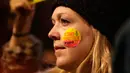 Seorang wanita menempelkan stiker ke pipinya dalam unjuk rasa di luar Downing Street, London, Senin (30/1). Ratusan orang di London turun ke jalan menentang kebijakan Presiden AS Donald Trump menyangkut kependudukan dan imigrasi. (AP Photo/Alastair Grant)