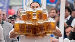 Oliver Struempfel berjalan membawa sejumlah gelas bir besar dalam festival tradisional Gillamoos di Abensberg, Jerman, Minggu (3/9). Struempfel berhasil memecahkan rekor membawa 29 gelas bir dengan berjalan sejauh 40 meter. (Matthias Balk/dpa via AP)