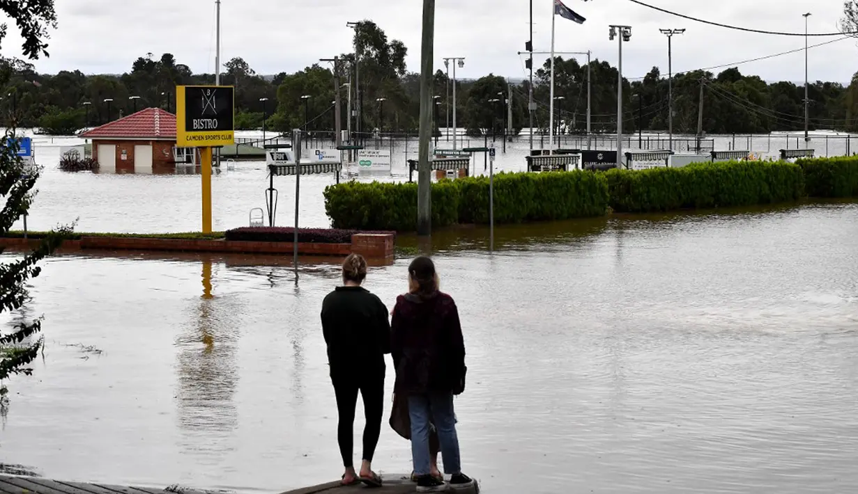 Warga melihat banjir yang meninggi dekat area komersial di pinggiran barat daya Camden, Sydney, Australia, Selasa (8/3/2022). (Muhammad FAROOQ/AFP)