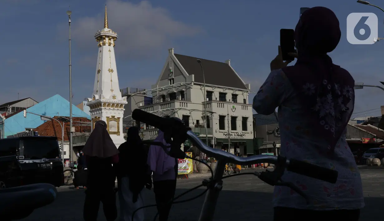 Pesepeda berfoto di perempatan Tugu Pal Putih Yogyakarta, Sabtu (26/12/2020). Kini, proses penataan kembali kawasan Tugu Pal Putih Yogyakarta rampung dilakukan, dan area yang menjadi salah satu ikon kota Yogya terlihat lebih rapi tanpa gangguan kabel melintang. (Liputan6.com/Helmi Fithriansyah)