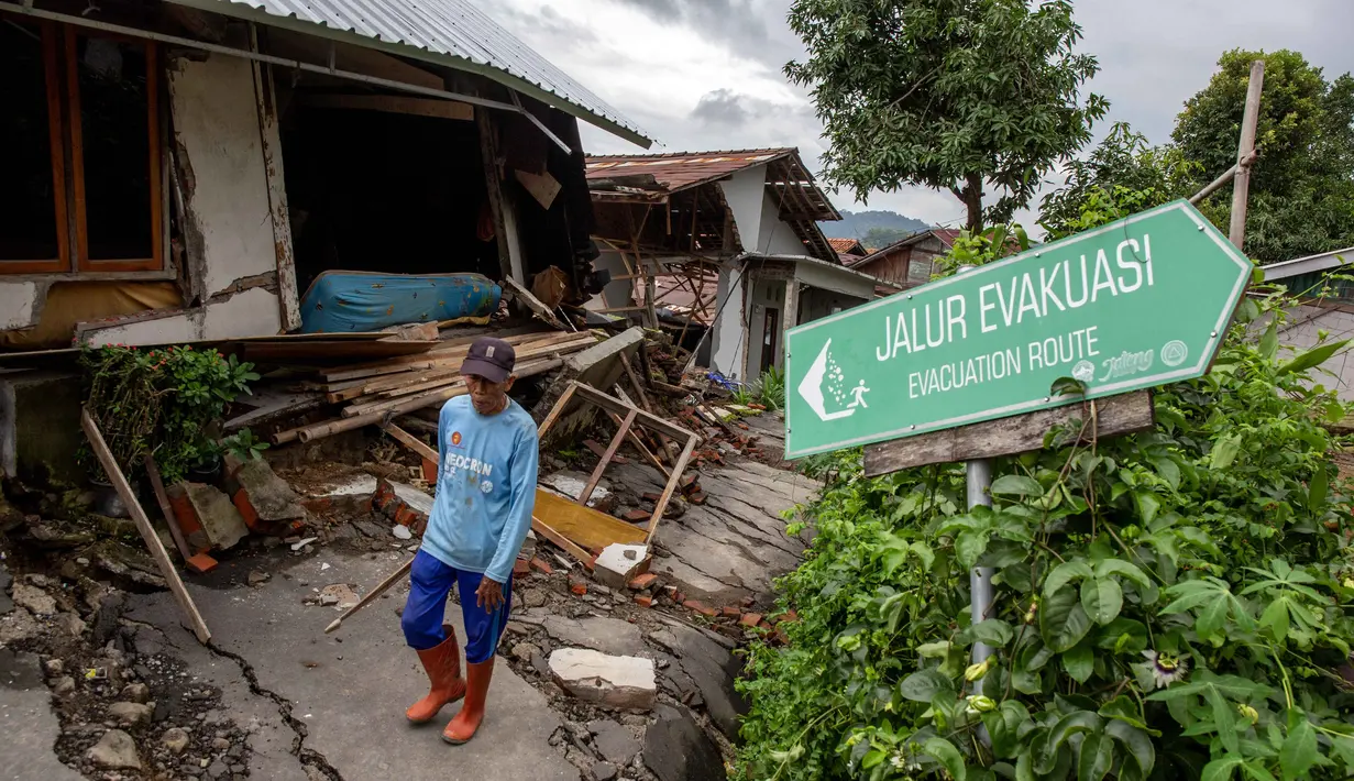 Seorang pria berjalan di samping rumah-rumah yang rusak setelah pergerakan tanah melanda permukiman mereka di desa Padasari, Tegal, Jawa Tengah, Senin 9 Februari 2026. Fenomena tanah bergerak di Desa Padasari, Kecamatan Jatinegara, Kabupaten Tegal, Jawa Tengah masih terus terjadi. (DEVI RAHMAN/AFP)