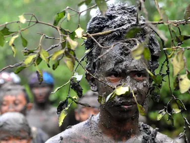 Warga Bali mengunakan akar pohon di kepalanya saat mengikuti tradisi mandi lumpur atau dikenal Mebuug-buugan di desa Kedonganan, Denpasar, Bali (10/3). Mebuug-buugan diadakan sehari usai hari raya Nyepi. (AFP/Sonny Tumbelaka)