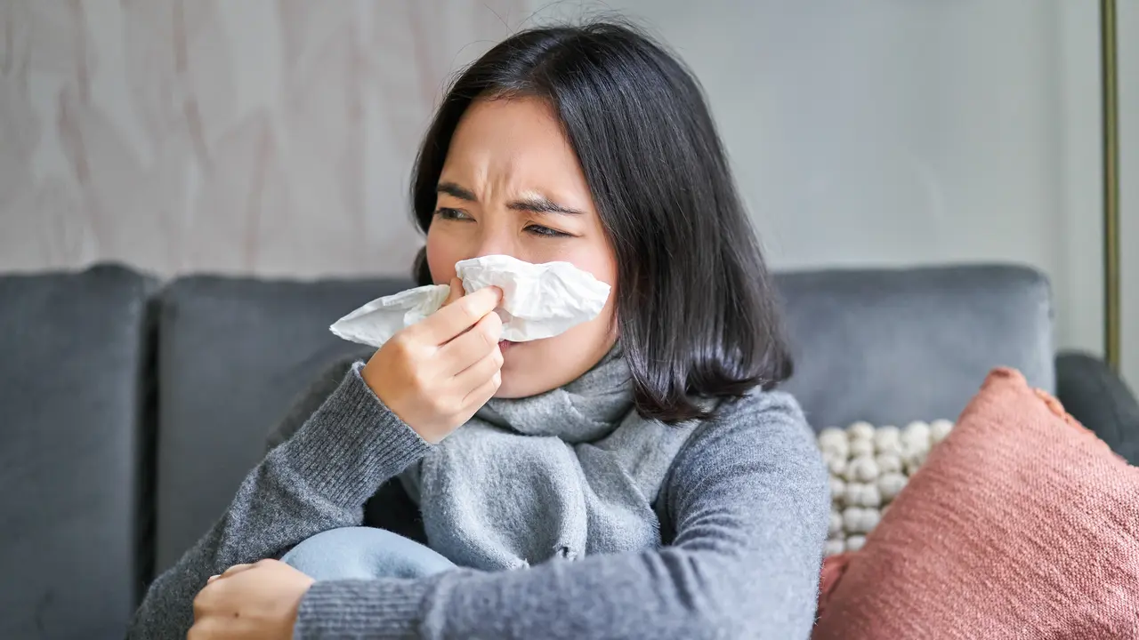 Seorang perempuan sedang mengusap hidungnya menggunakan tisu (Foto Dok: Freepik/benzoix)