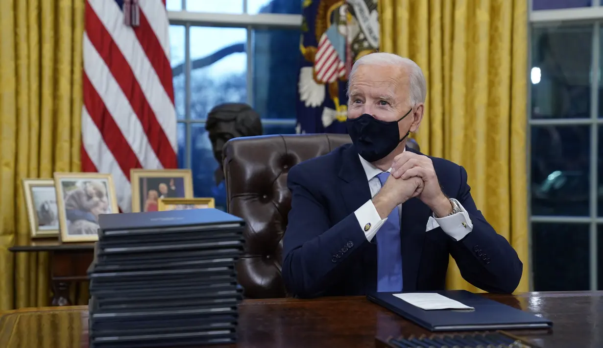 Presiden Joe Biden saat berada pertamanya di Ruang Oval, Gedung Putih di Washington, Rabu (20/1/2021). Pada hari pertamanya menjabat, Presiden Amerika Serikat Joe Biden menandatangani sejumlah tindakan eksekutif di Gedung Putih. (AP Photo/Evan Vucci)