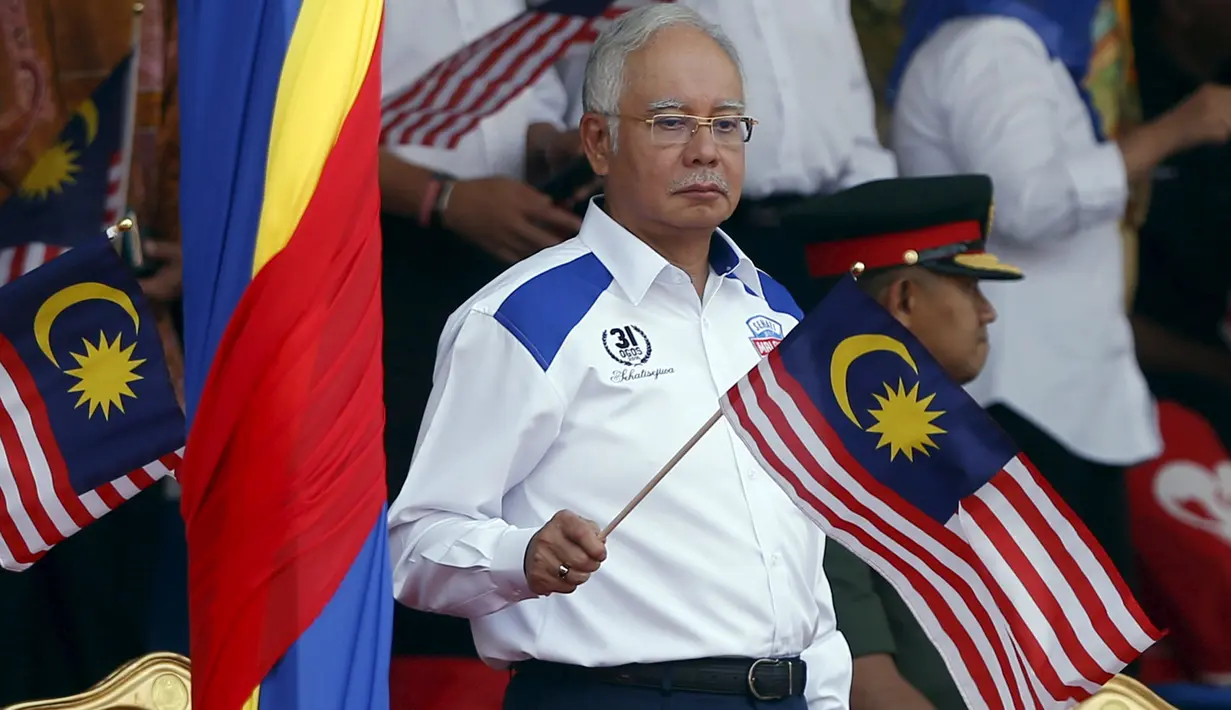 PM Najib Razak mengibarkan bendera nasional Malaysia saat merayakan Hari Kemerdekaan ke-58 di Kuala Lumpur, Senin (31/8/2015).  Perayaan kemerdekaan kali ini dilakukan di tengah desakan mundur kepada PM Najib. (REUTERS/Olivia Harris)